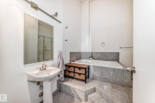Bathroom featuring a pedestal sink, a wall-mounted mirror, and a built-in jetted tub - 1003 10179 105 Street Nw, Edmonton, AB - Indoor Photo Showing Bathroom