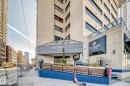 Multistory building with a glass-covered entryway, concrete facade, extensive window lines, and a ramp entrance - 1003 10179 105 Street Nw, Edmonton, AB  - Outdoor 