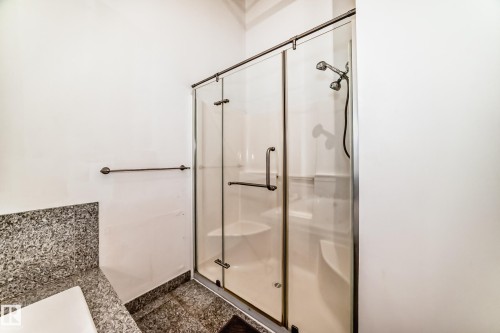 Glass-enclosed shower with a multi-function showerhead, integrated seating, and a bronze-finish towel bar - 1003 10179 105 Street Nw, Edmonton, AB - Indoor Photo Showing Bathroom