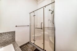 Glass-enclosed shower with a multi-function showerhead, integrated seating, and a bronze-finish towel bar - 