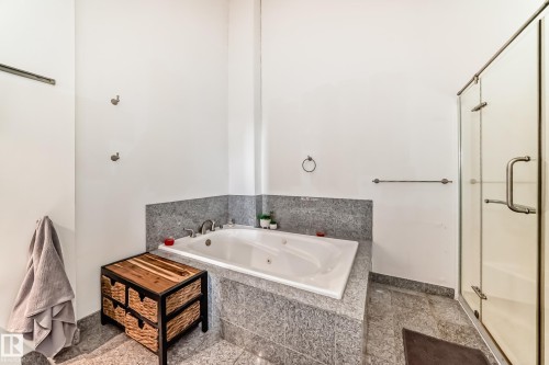 White soaking tub with deck-mounted fixtures set within a stone surround - 1003 10179 105 Street Nw, Edmonton, AB - Indoor Photo Showing Bathroom