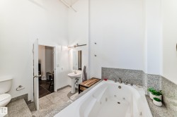 Spacious bathroom featuring a white jetted tub, a pedestal sink, and a commode - 