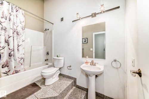 Bathroom featuring a white pedestal sink, a white toilet, and a white tub with shower - 1003 10179 105 Street Nw, Edmonton, AB - Indoor Photo Showing Bathroom