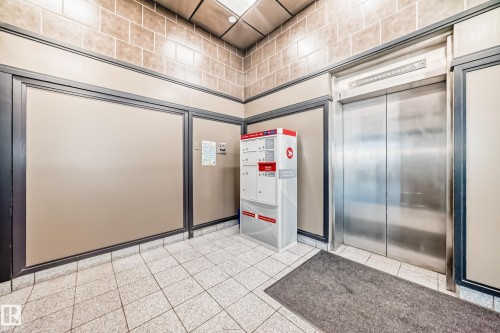 Building lobby featuring a stainless steel elevator, tiled flooring, and a beige and brown wall treatment - 1003 10179 105 Street Nw, Edmonton, AB - Indoor Photo Showing Other Room