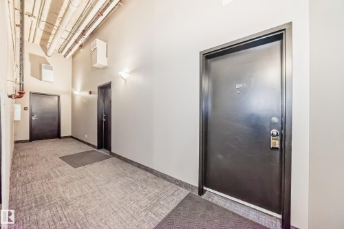 Common area hallway featuring durable carpet tile flooring and sconce lighting - 1003 10179 105 Street Nw, Edmonton, AB - Indoor Photo Showing Other Room