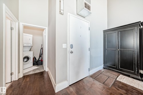 Dedicated laundry alcove with stackable washer and dryer, wood-finish flooring, and light gray wall paint - 1003 10179 105 Street Nw, Edmonton, AB - Indoor Photo Showing Laundry Room