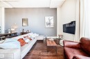 Expansive living space featuring wood-finish flooring, exposed ceiling beams, and a wall-mounted television - 1003 10179 105 Street Nw, Edmonton, AB  - Indoor Photo Showing Living Room 
