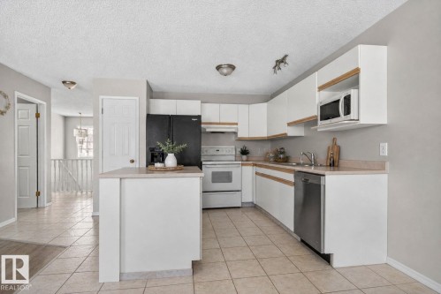 Kitchen featuring white cabinetry, light countertops, an undermount sink, and stainless steel dishwasher - 64 3311 58 Street, Edmonton, AB - Indoor Photo Showing Kitchen