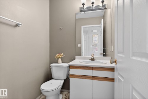 Bathroom featuring a white toilet, light-toned walls, and a vanity with a white countertop and base cabinetry - 64 3311 58 Street, Edmonton, AB - Indoor Photo Showing Bathroom