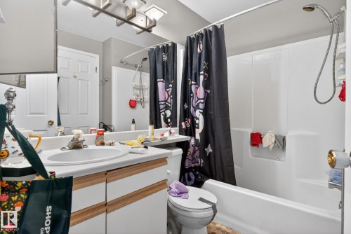 Bathroom featuring a single vanity with an integrated sink, white countertop, and wood-finish cabinetry - 64 3311 58 Street, Edmonton, AB - Indoor Photo Showing Bathroom