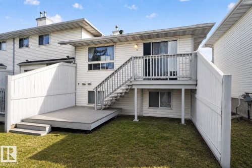Rear exterior showcasing a ground-level deck with steps, a raised deck with railing, and a sliding glass door - 64 3311 58 Street, Edmonton, AB - Outdoor With Deck Patio Veranda With Exterior