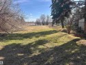 Expansive lot featuring a large grassy area, mature trees, and a distant water body - 5013 50 Avenue, Fawcett, AB 