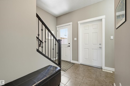 Entryway featuring a paneled door, ceramic tile flooring, and a staircase with wrought iron balusters - 11 94 Longview Drive, Spruce Grove, AB - Indoor Photo Showing Other Room