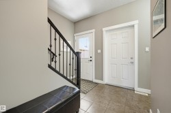 Entryway featuring a paneled door, ceramic tile flooring, and a staircase with wrought iron balusters - 