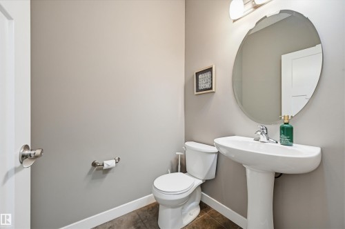 Pedestal sink with chrome faucet, oval mirror, and overhead vanity lighting - 11 94 Longview Drive, Spruce Grove, AB - Indoor Photo Showing Bathroom
