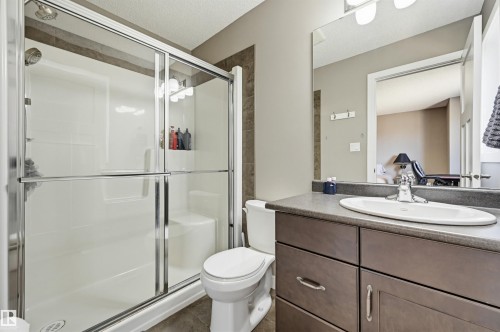 Full bathroom featuring a shower with a sliding glass enclosure, integrated seating, and a showerhead - 11 94 Longview Drive, Spruce Grove, AB - Indoor Photo Showing Bathroom