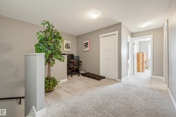 Expansive carpeted landing featuring neutral wall paint, white trim, a built-in closet with bi-fold doors, and recessed ceiling lights - 