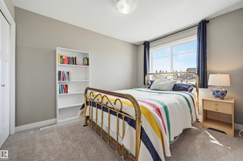 Carpeted room featuring a large window with dark curtains, light gray wall paint, and a built-in closet with a white door - 11 94 Longview Drive, Spruce Grove, AB - Indoor Photo Showing Bedroom
