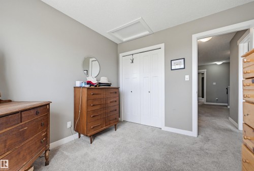 Light gray wall paint, white trim, light gray carpeting, bi-fold closet doors, and a ceiling access panel - 11 94 Longview Drive, Spruce Grove, AB - Indoor Photo Showing Bedroom