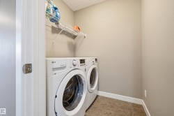 Dedicated laundry area featuring a front-loading washer and dryer, a wire shelving unit, neutral wall paint, and tile flooring - 