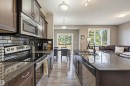 Kitchen featuring dark wood-finish cabinetry, stainless steel appliances, dark subway tile backsplash, and stone countertops - 11 94 Longview Drive, Spruce Grove, AB  - Indoor Photo Showing Kitchen With Stainless Steel Kitchen With Double Sink With Upgraded Kitchen 