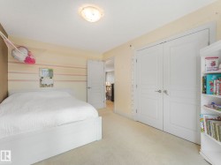 Room featuring neutral-toned carpeting, a light-colored wall with horizontal striped detailing, and white bi-fold closet doors with paneling - 