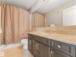 Bathroom featuring a vanity with a light-toned countertop, integrated sink, and chrome fixtures - 