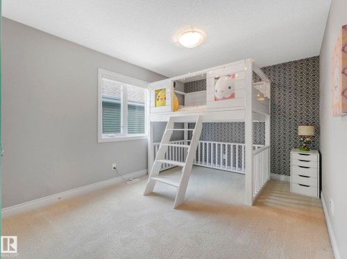 Spacious room featuring light-colored carpeting, a single window with blinds, and a built-in white bunk bed structure - 932 Summerside Link, Edmonton, AB - Indoor Photo Showing Bedroom