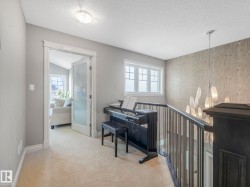 Upper-level landing featuring plush carpeting, a modern chandelier, and a wood-panel accent wall - 