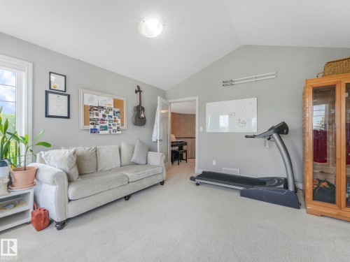 Carpeted room featuring a vaulted ceiling and a large window - 932 Summerside Link, Edmonton, AB - Indoor Photo Showing Living Room