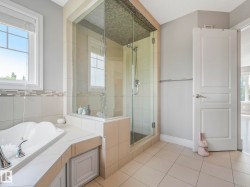 Bathroom featuring a glass-enclosed shower with mosaic tile ceiling, a built-in soaking tub with chrome fixtures, a tiled surround, and a clear window with blinds - 