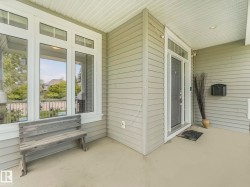 Covered front porch featuring light gray horizontal siding and a dark gray entry door - 