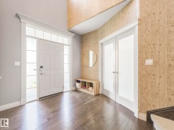 Foyer with wood-finish flooring, a paneled entry door with sidelights and transom, and double frosted-glass French doors - 