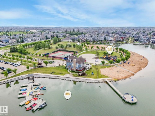 Waterfront recreational area featuring a multi-level boat dock, a sandy beach, and a children's playground - 932 Summerside Link, Edmonton, AB - Outdoor With Body Of Water With View