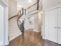 Grand entryway featuring a curved staircase with dark wood-finish banister and carpeted treads, wood-finish flooring, and a second-story landing with matching banister - 932 Summerside Link, Edmonton, AB  - Indoor Photo Showing Other Room 