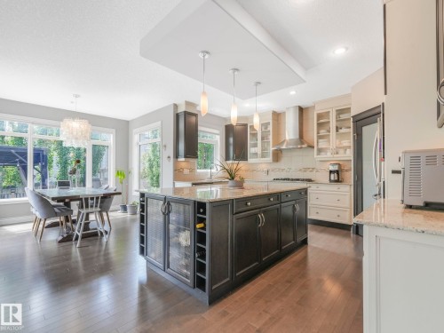 Gourmet kitchen featuring a large island with integrated wine storage and beverage cooler, granite countertops, and stainless steel appliances - 932 Summerside Link, Edmonton, AB - Indoor Photo Showing Kitchen With Upgraded Kitchen