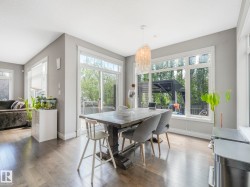 Spacious dining area featuring wood-finish flooring, a contemporary chandelier, multiple large windows, and a sliding glass door - 