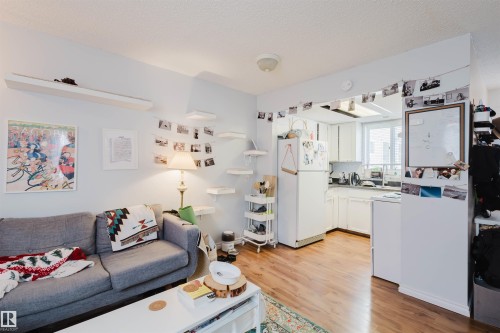 Living area featuring wood-finish flooring, white walls, and built-in shelving - 10831 80 Avenue, Edmonton, AB - Indoor