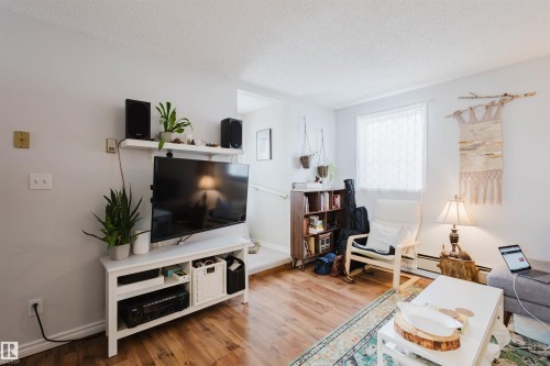Living area featuring wood-finish flooring, white baseboards, and light neutral wall paint - 10831 80 Avenue, Edmonton, AB - Indoor Photo Showing Living Room