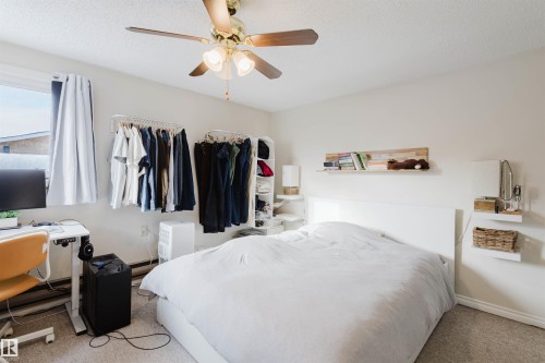 Bedroom featuring light neutral wall paint, a ceiling fan with integrated lighting, carpeted flooring, a window with vertical blinds, and white baseboards - 10831 80 Avenue, Edmonton, AB - Indoor Photo Showing Bedroom