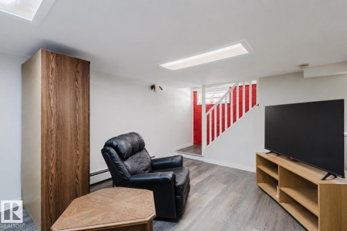 Lower level space featuring wood-finish flooring, white painted walls, and overhead rectangular lighting fixtures - 10831 80 Avenue, Edmonton, AB - Indoor