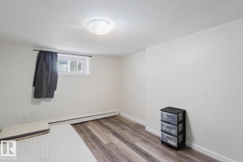 Spacious room featuring wood-finish flooring, white baseboards, and a flush-mount ceiling light fixture - 10831 80 Avenue, Edmonton, AB - Indoor Photo Showing Other Room