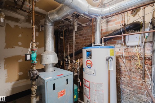 Mechanical room featuring a water heater, boiler system, and visible copper and galvanized piping - 10831 80 Avenue, Edmonton, AB - Indoor Photo Showing Basement