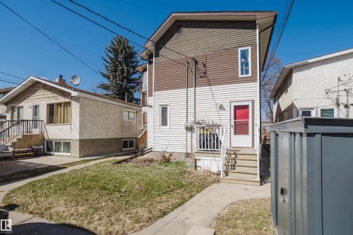 Exterior featuring white and brown siding, a red entry door, a small balcony, and an exterior storage shed - 10831 80 Avenue, Edmonton, AB - Outdoor