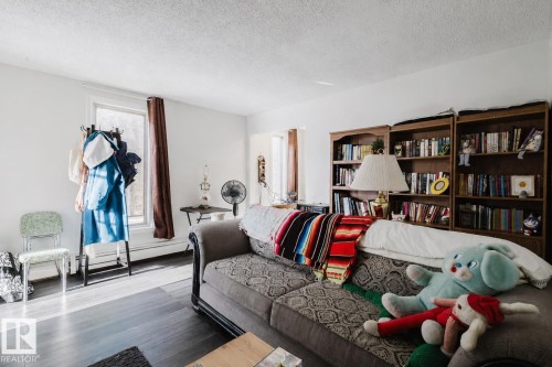 Spacious living area featuring dark wood-finish flooring, white walls, and multiple windows - 10831 80 Avenue, Edmonton, AB - Indoor