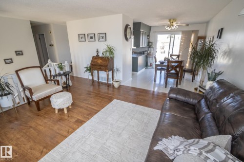 Open-concept living area featuring wood-finish flooring, white wall tones, and a staircase with white balusters - 4417 46A St, St. Paul Town, AB - Indoor Photo Showing Living Room