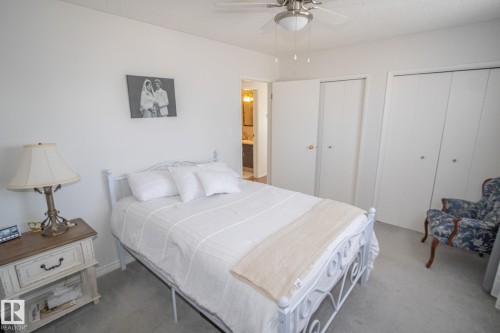 Bedroom featuring light grey carpet, a ceiling fan with integrated lighting, a closet with bi-fold doors, a second closet with a standard door, and neutral white wall paint - 4417 46A St, St. Paul Town, AB - Indoor Photo Showing Bedroom