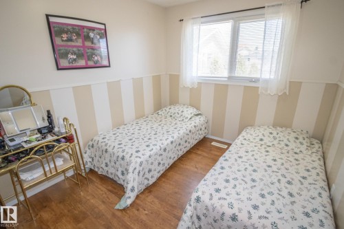 Room featuring wood-finish flooring, a window with blinds and sheer curtains, and striped wall paneling - 4417 46A St, St. Paul Town, AB - Indoor Photo Showing Bedroom