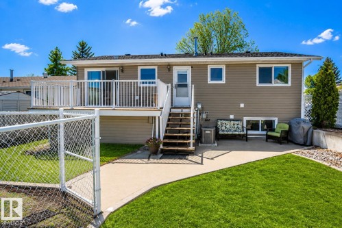 Rear exterior featuring a spacious elevated deck with white railings, direct stair access to the ground level, and a walk-out patio - 4417 46A St, St. Paul Town, AB - Outdoor With Deck Patio Veranda