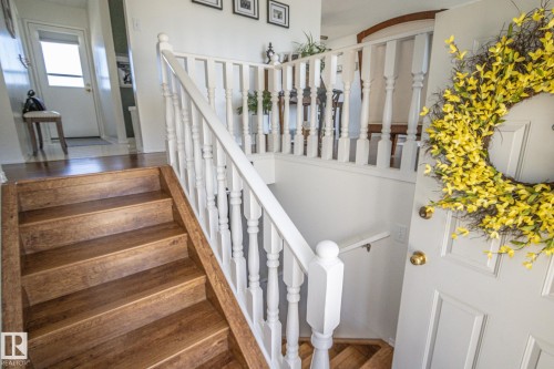 Entryway featuring wood-finish stairs with a white baluster railing and paneled door with brass hardware - 4417 46A St, St. Paul Town, AB - Indoor Photo Showing Other Room